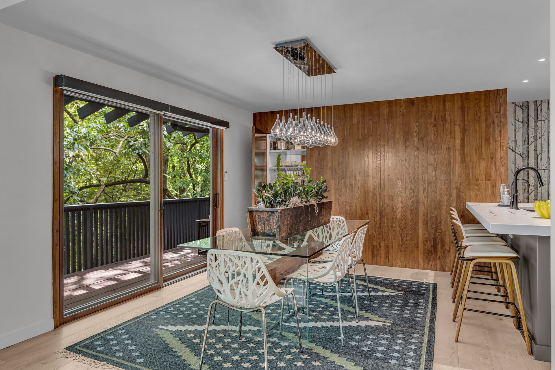 Dining nook with glass table and wood accent wall