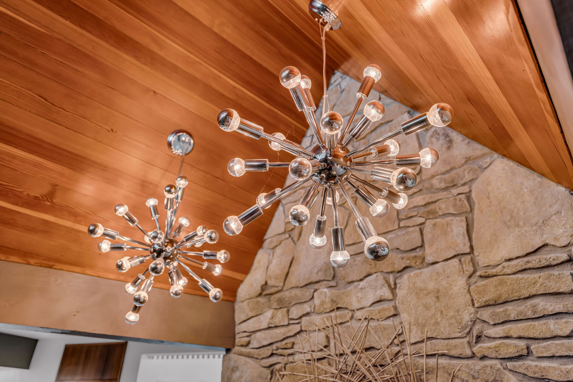 Pair of sputnik chandeliers against the wood ceiling