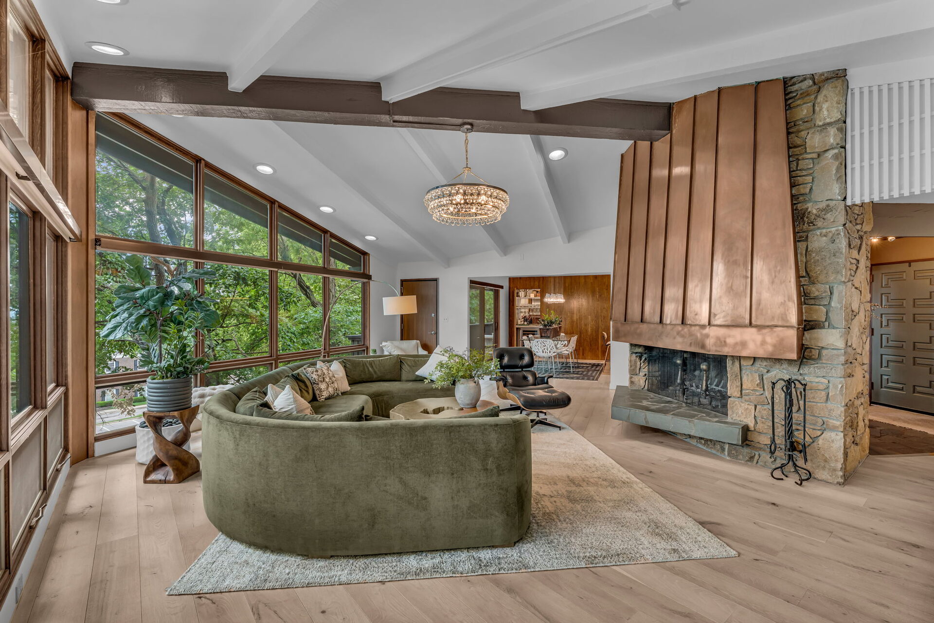 Living room with copper-clad fireplace surround, stone chimney, and beamed ceiling at the Raymond Rice House